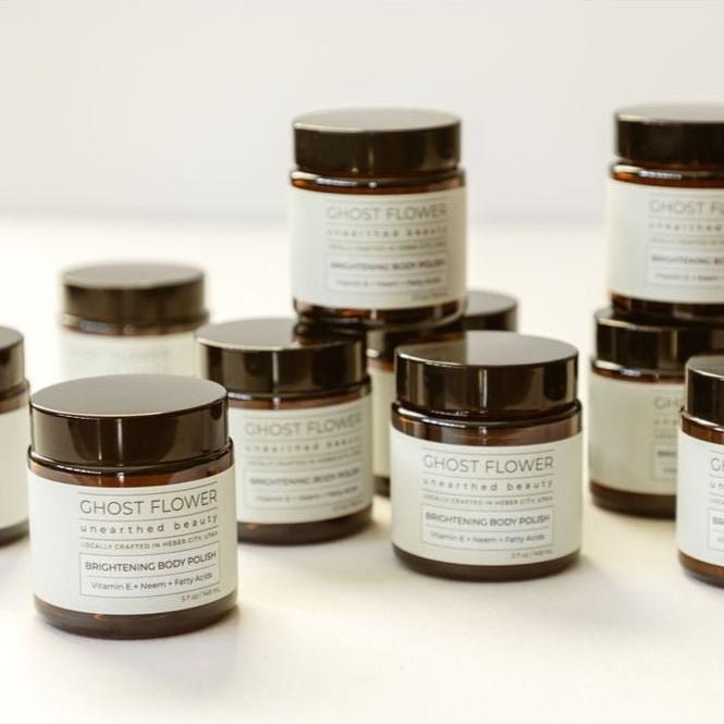 product-photo-with-a-bunch-of-brightening-body-polish-brown-jars-with-white-labels-and-black-lids